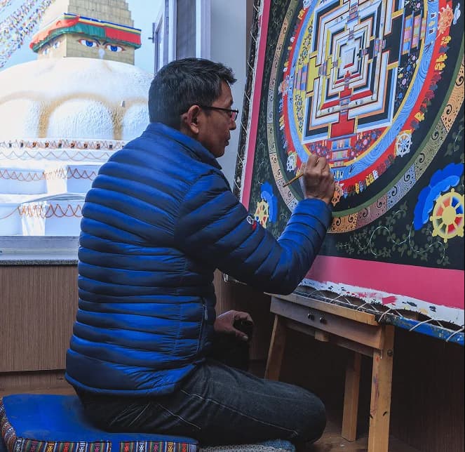 Artisan painting fine details on a traditional thangka